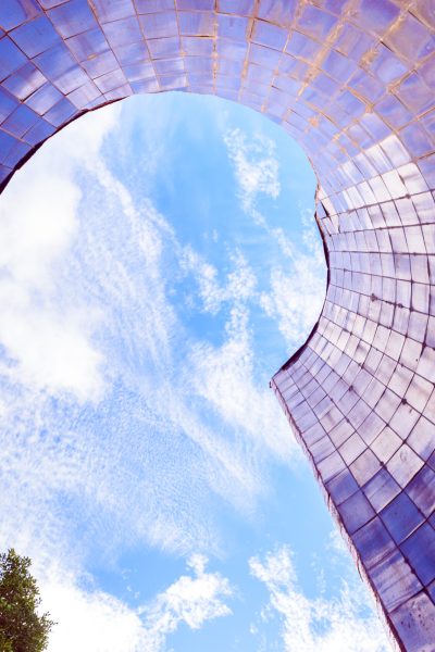Conical smooth tile surface pointing to the blue sky with reflections of an abstract background.